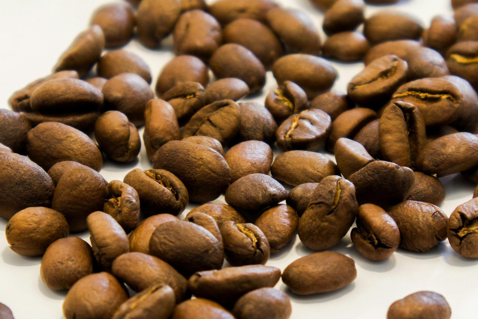 Macro shot of roasted coffee beans on a white background, perfect for café promotions.